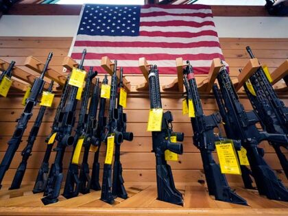 A variety of AR-15-style rifles are displayed under an American flag at the Kittery Tradin