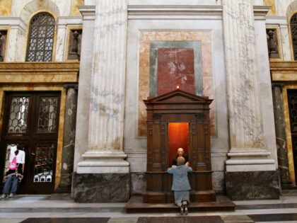 A woman makes confession with a priest as girls take in the scenery at Saint Paul's B