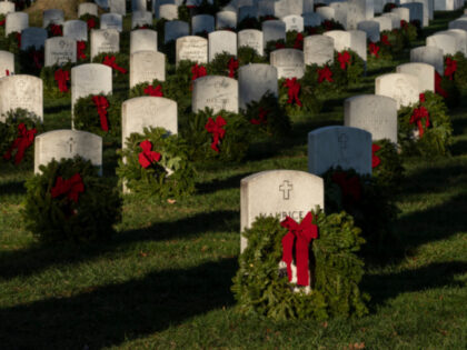 Christmas wreaths placed by volunteers sit in front of headstones at Arlington National Ce