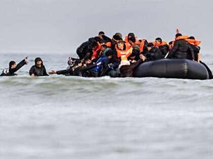 Migrants board a smuggler's boat in an attempt to cross the English Channel, on the beach