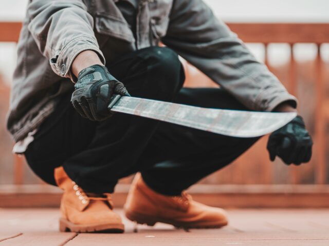 A person wearing a mask and holding a knife, Unsplash