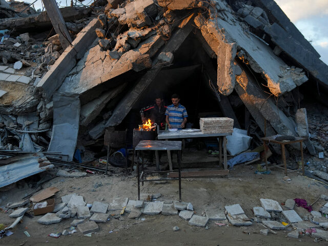 A man sells bread under the destruction of his bakery destroyed by the Israeli air and gro