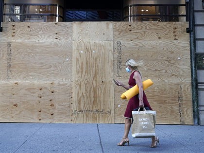 TOPSHOT - A woman walks by a boarded up Cartier store on 5th Avenue in New York City June