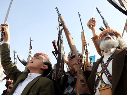 Yemen's Houthi supporters brandish weapons and chant slogans during a protest, staged agai