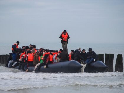 Migrants board a smuggler's inflatable dinghy as they attempt to cross the English Channel