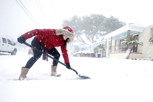 NEW ORLEANS, LOUISIANA - JANUARY 21: A woman shovels snow from her driveway in the Gentill