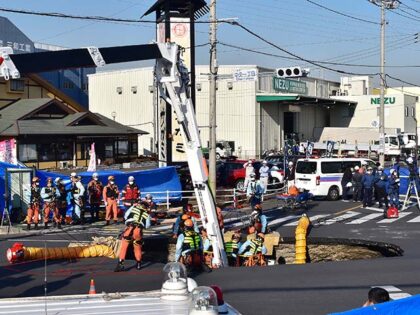 Firefighters work to rescue a truck driver after his vehicle was swallowed up by a sinkhol