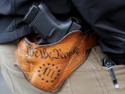 An attendee at a gun rights rally open-carries his gun in a holster that reads "We th