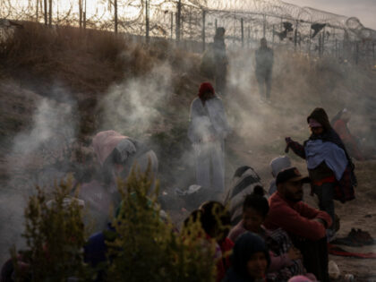 Migrants from Venezuela sit by a makeshift fire to warm up as they wait to enter and seek